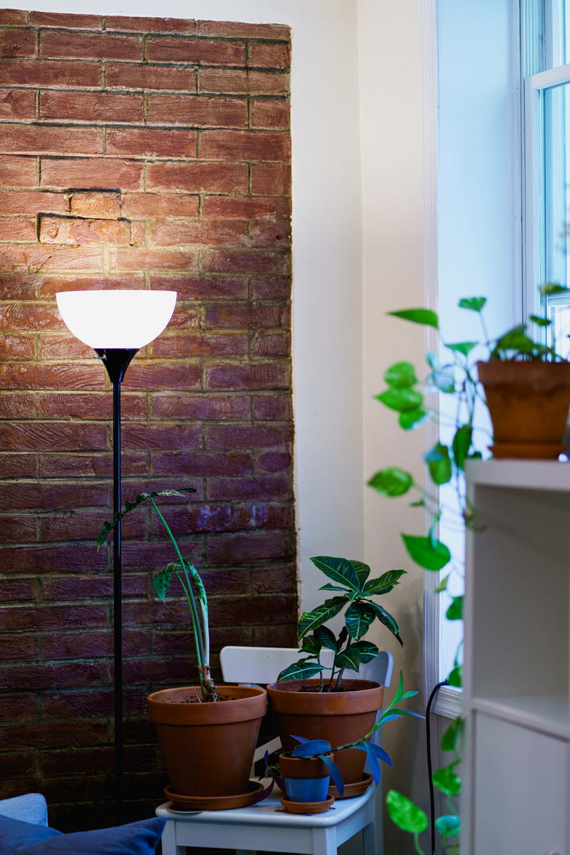 A lamp on a table next to a brick wall.