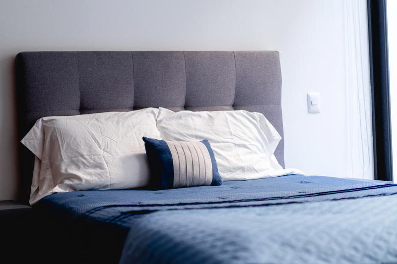 A bed with a blue comforter and pillows.