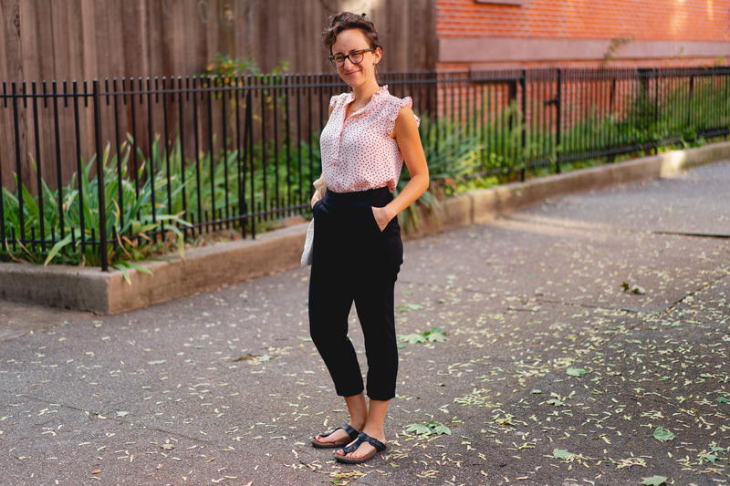 A woman wearing black pants and a pink top.