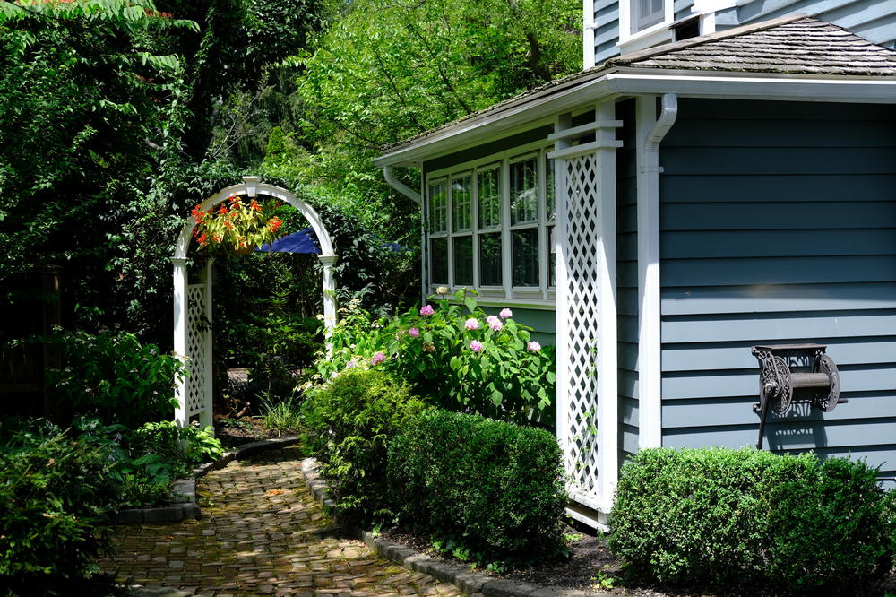 A pathway leading to a blue house with a white archway.