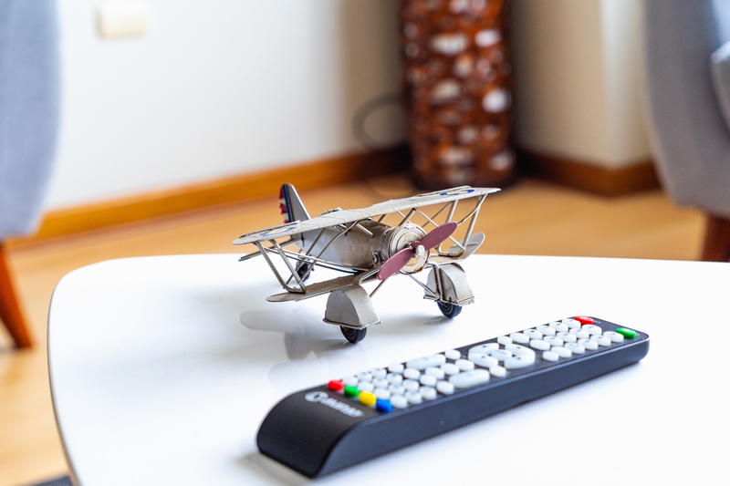 A toy airplane on a table next to a remote control.