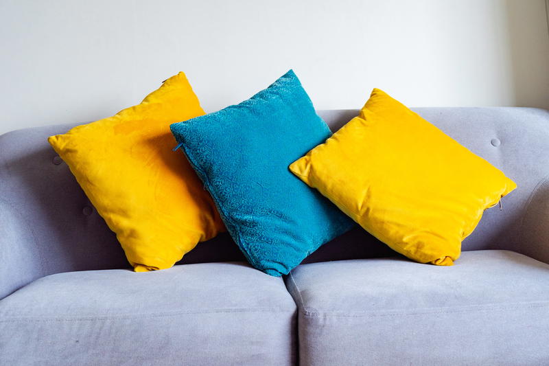 Three colorful pillows on a couch in a living room.