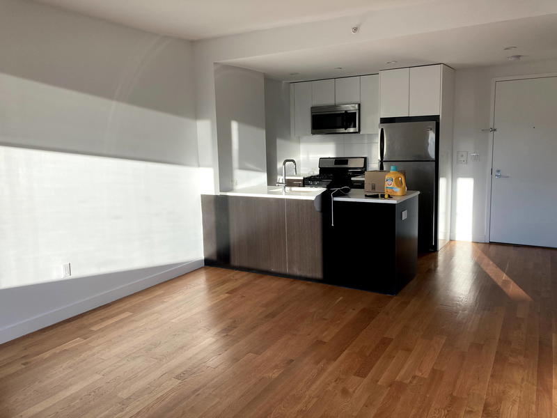 An empty kitchen with hardwood floors and a microwave.