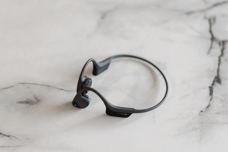 A black earphone sitting on a marble surface.