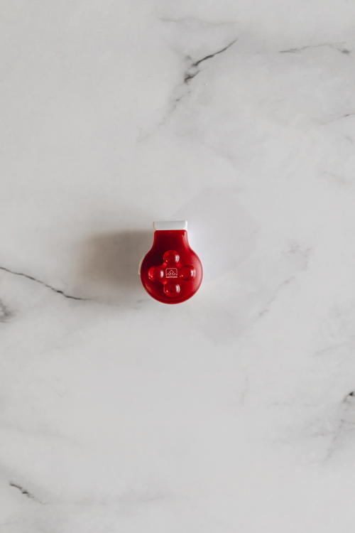 A red button sits on top of a marble surface.