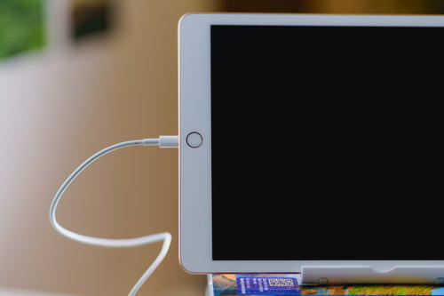 Charging cord plugged into a white ipad used as an external monitor as a sidecar for a home office setup