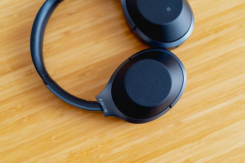 A pair of black headphones on a wooden table.