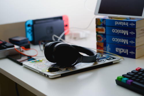 Sony noise canceling bluetooth headphones resting on a closed MacBook on a standing desk in a home office