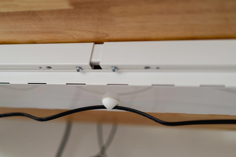 Close up of a wire holder for a standing desk.