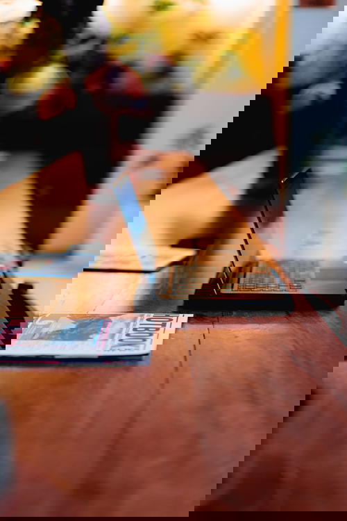 Black open laptop on a long communal wooden table at a trendy cafe in Mexico City