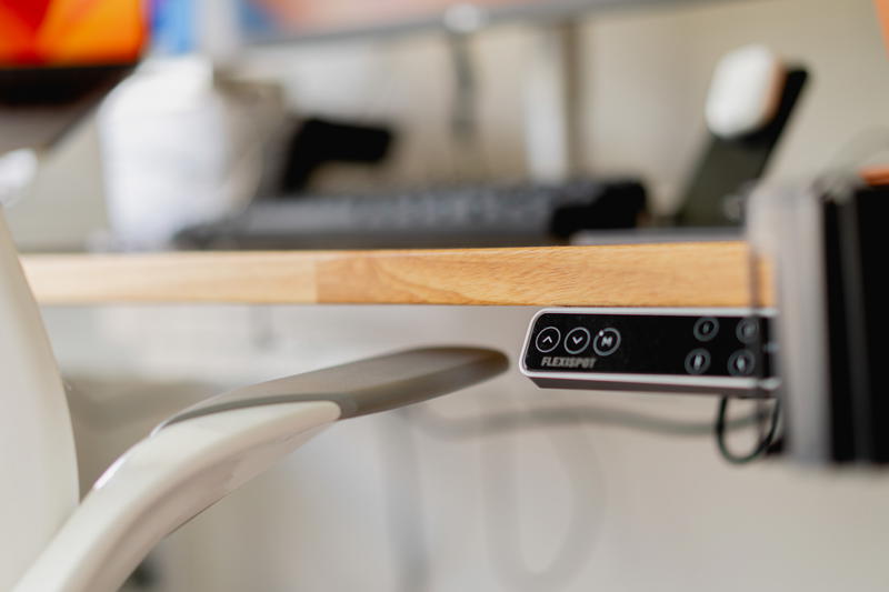A close up of an office chair arm close to a desk.