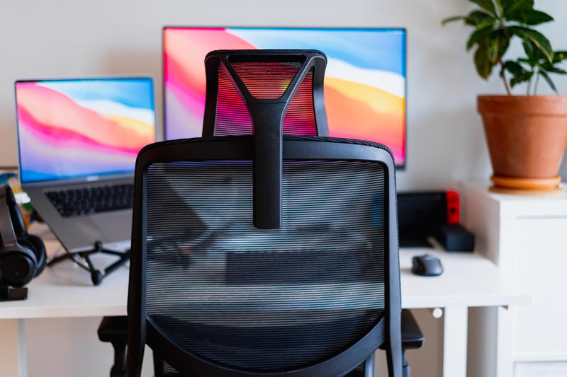 A desk with two monitors and a chair.