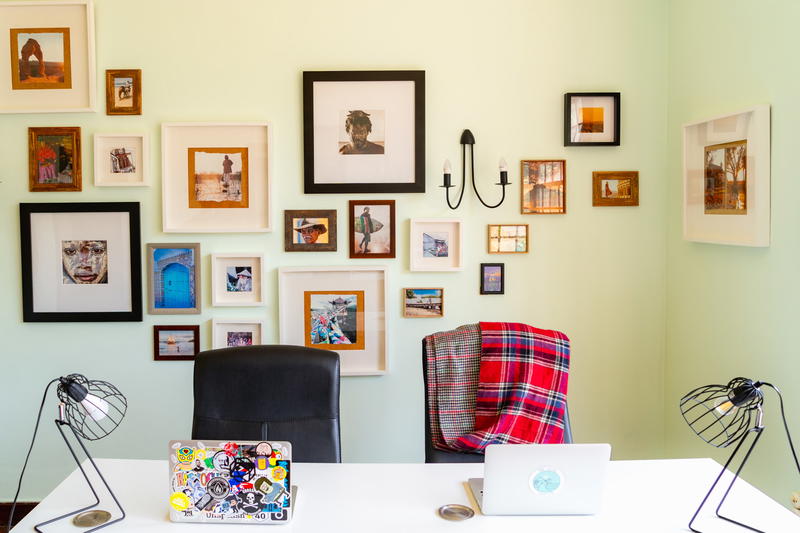 Chic coworking space setup with framed pictures on the wall and a large white shared desk with two laptops and black metal lamps